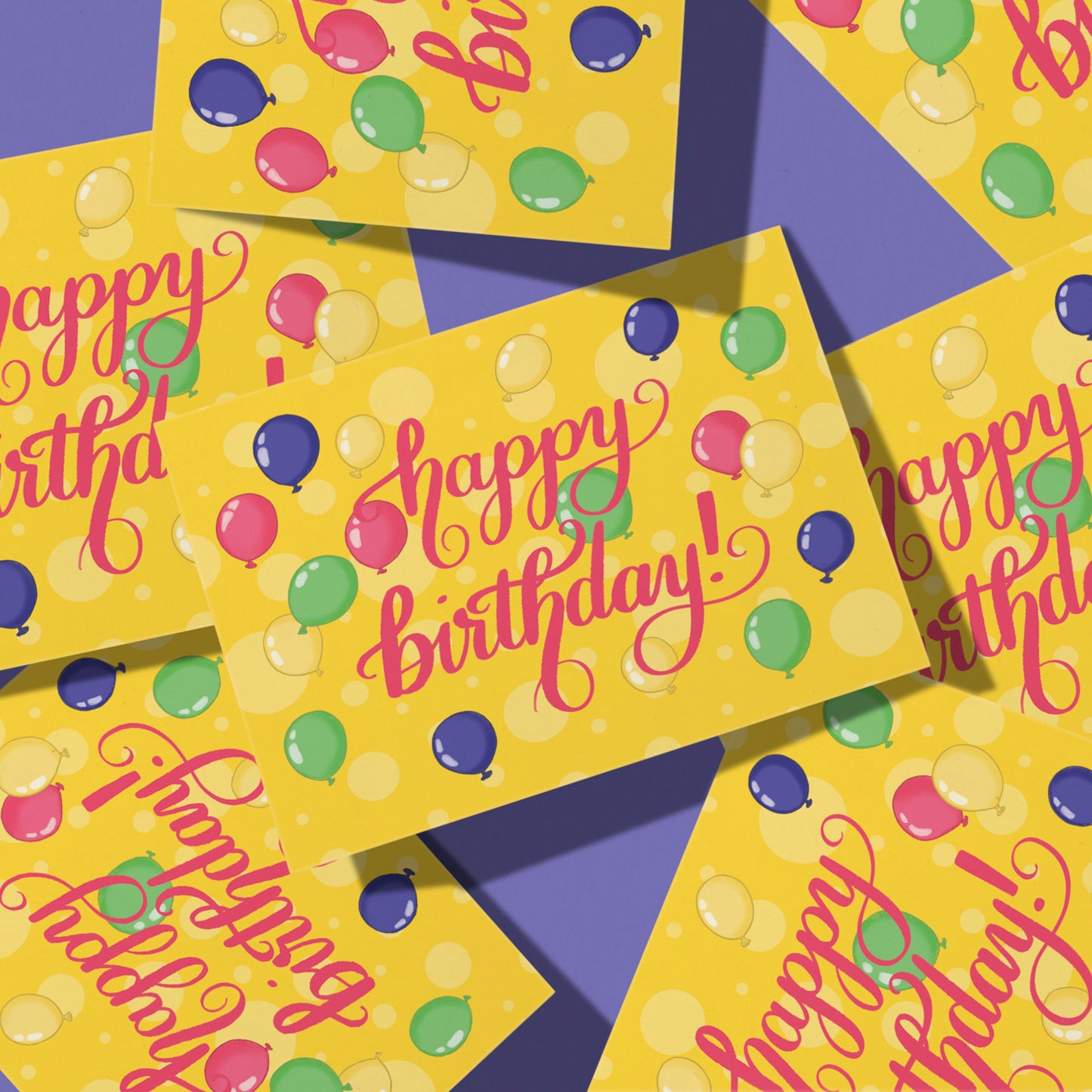 A yellow greeting card is covered with yellow dots and illustrations of pink, purple, yellow and green balloons. On the card are the words happy birthday lettered in bright pink. The card sits in a pile of copies of the same card on a purple background.