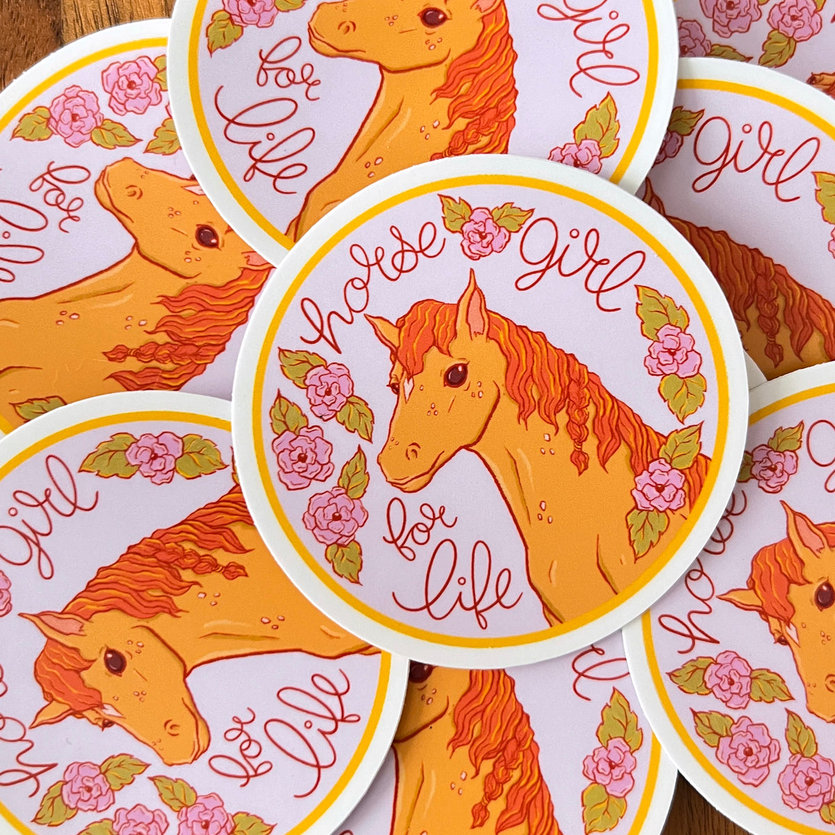 A pile of round purple stickers with horses and flowers all have the words Horse Girl for Life.