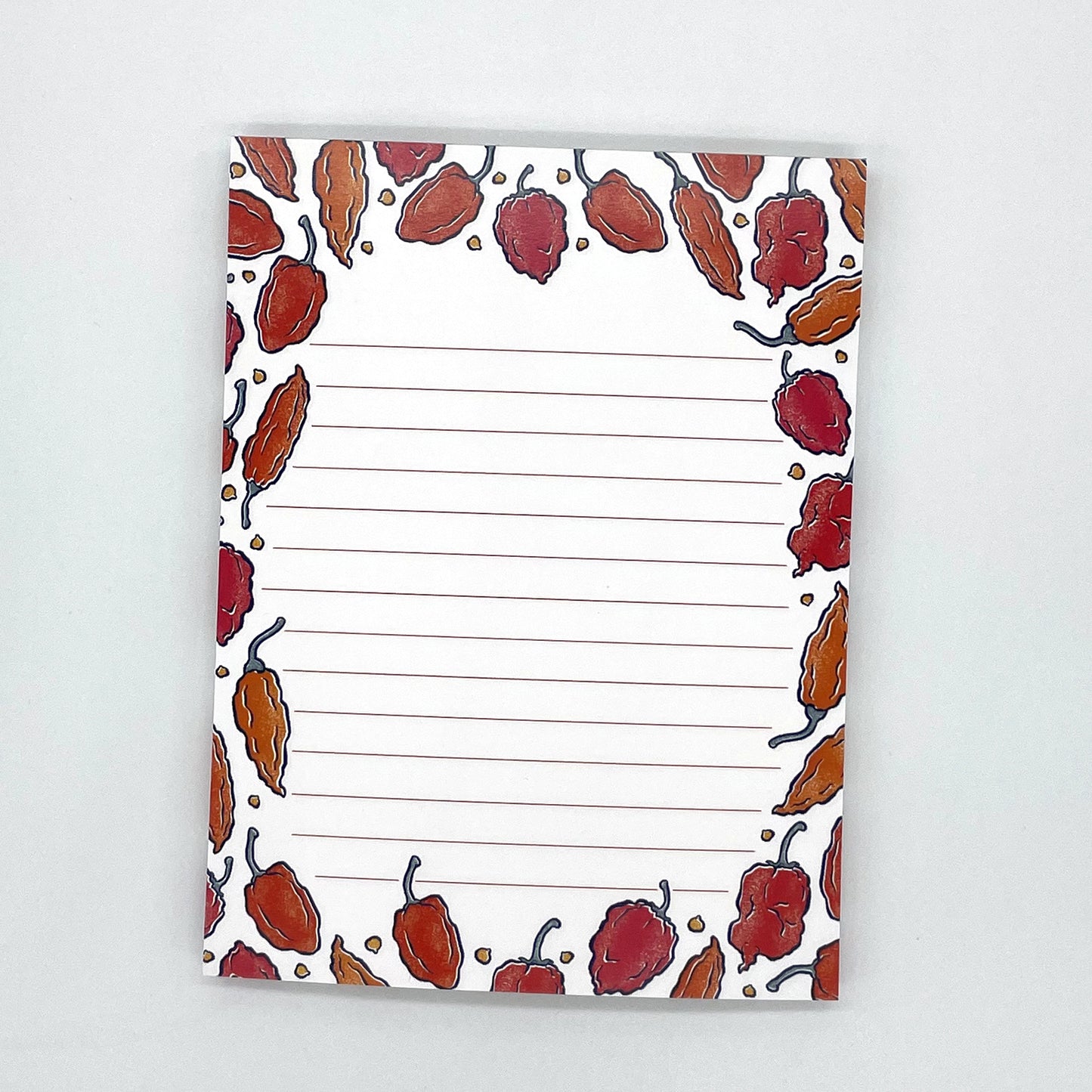 A white lined notepad features illustrations of hot peppers in orange and red.