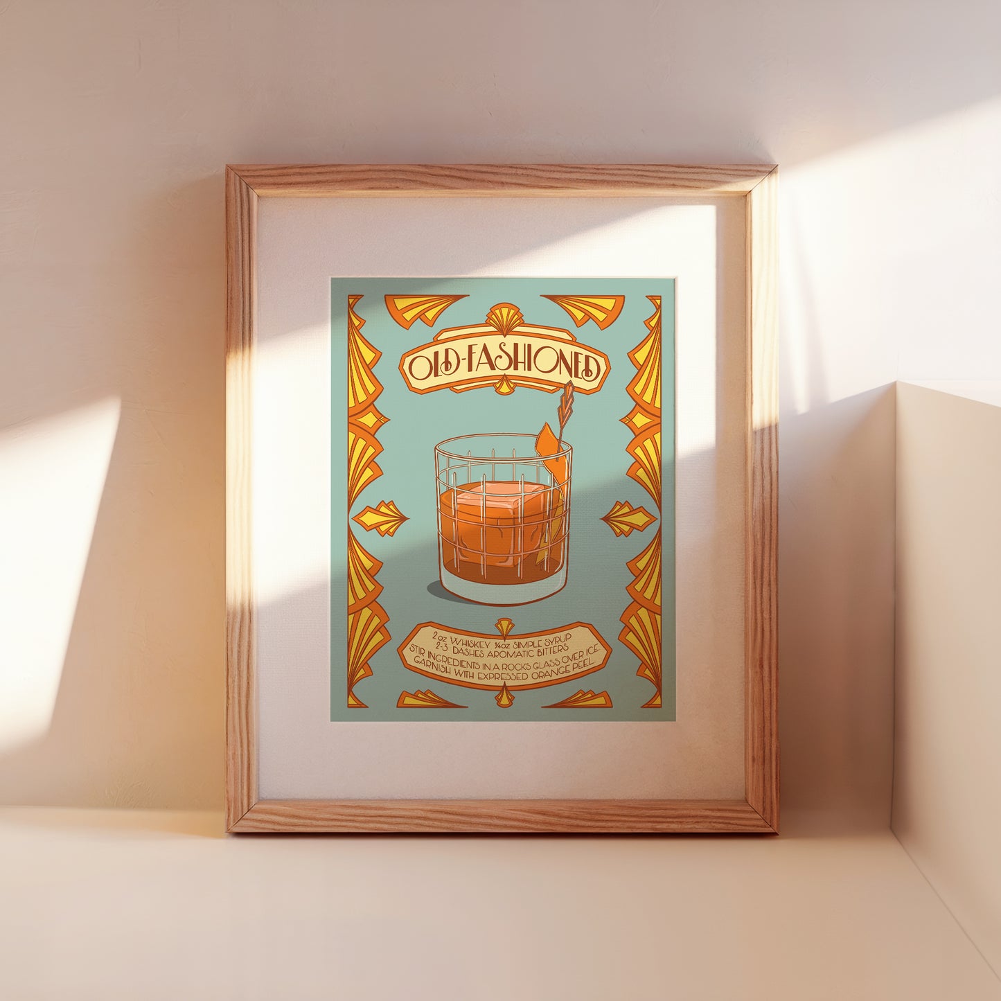 A framed illustrated cocktail recipe for an old-fashioned leans against a wall.