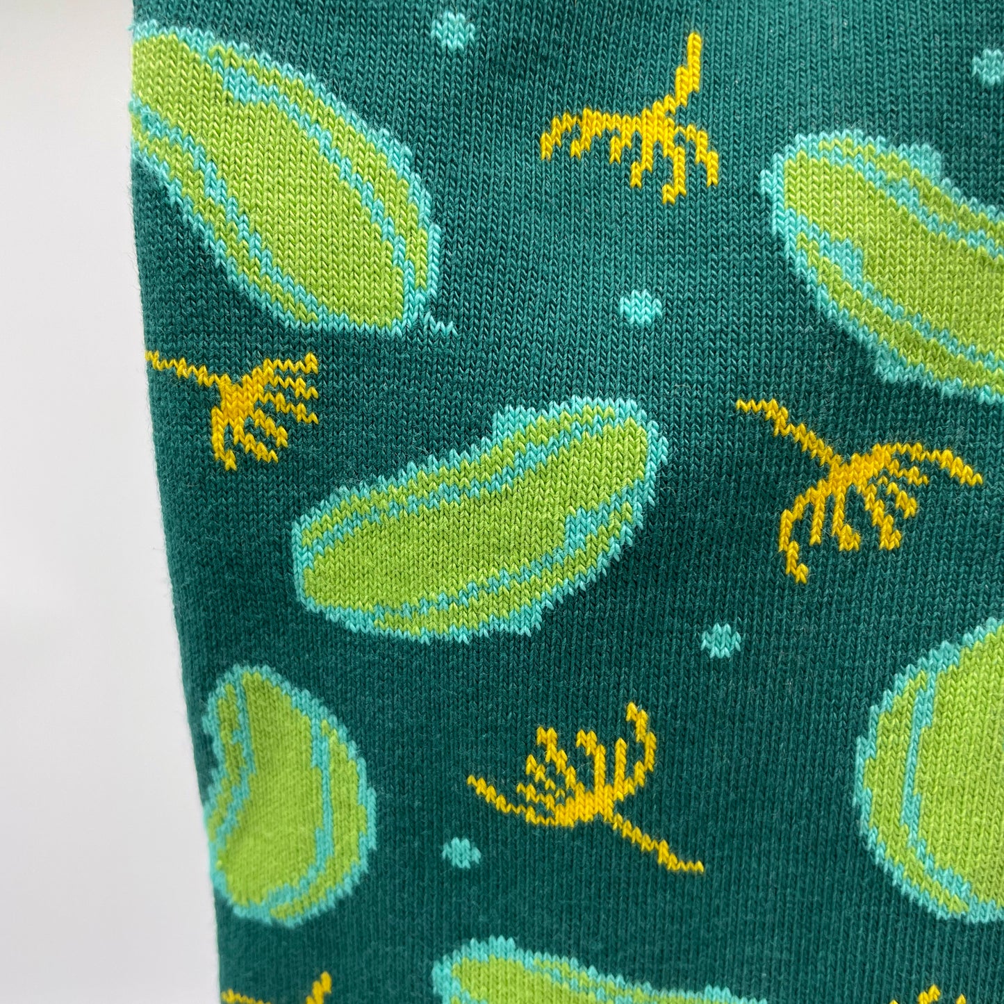 A close-up picture of a dill pickle pattern woven into organic cotton socks.