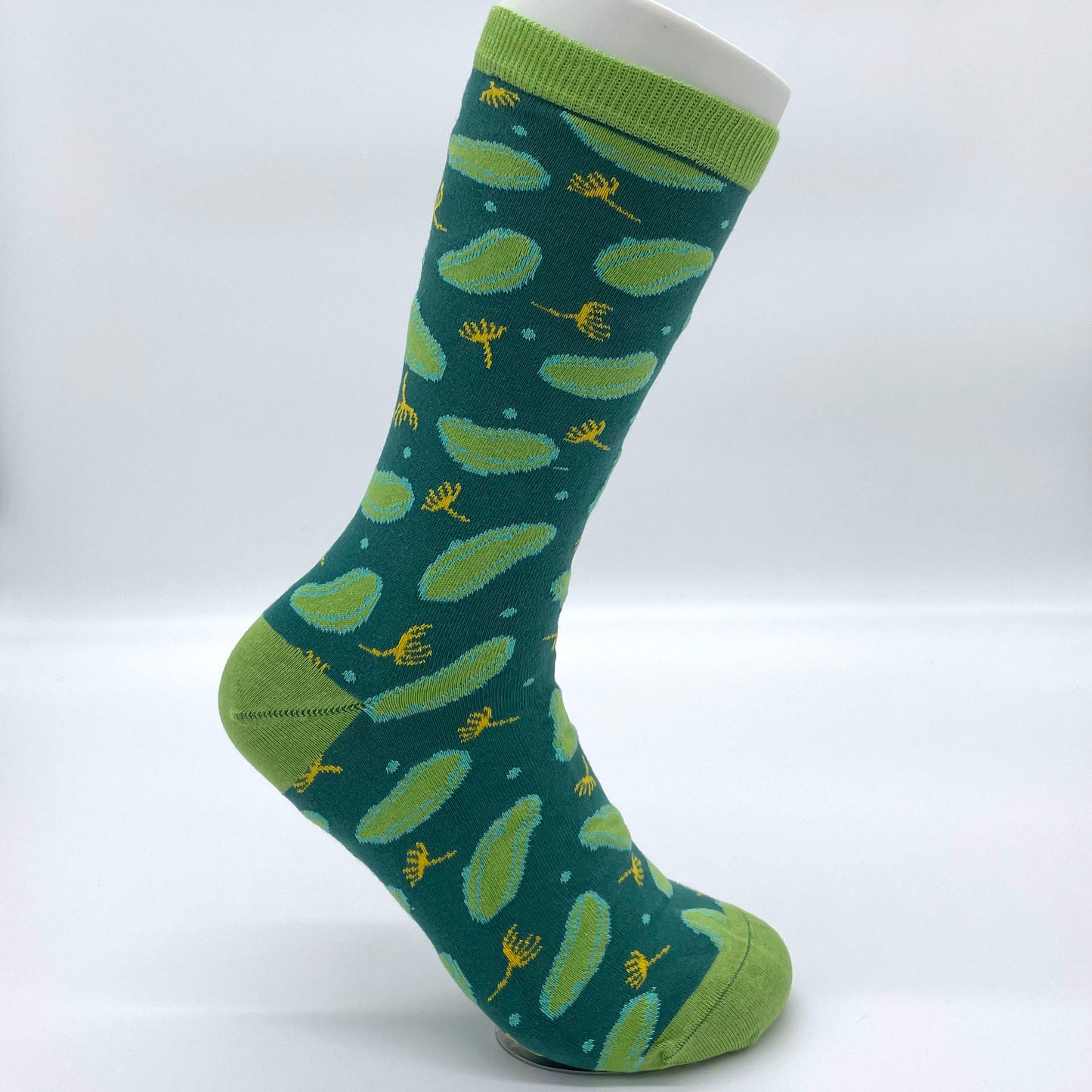 A white sock mannequin sports a dill pickle-patterned green sock. The welt, heel and toe are all light green.