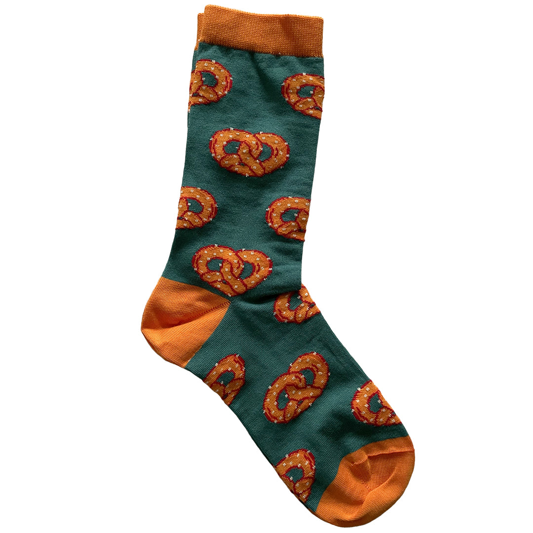 A pair of green socks patterned with orange salted pretzels has orange cuffs, heels and toes.