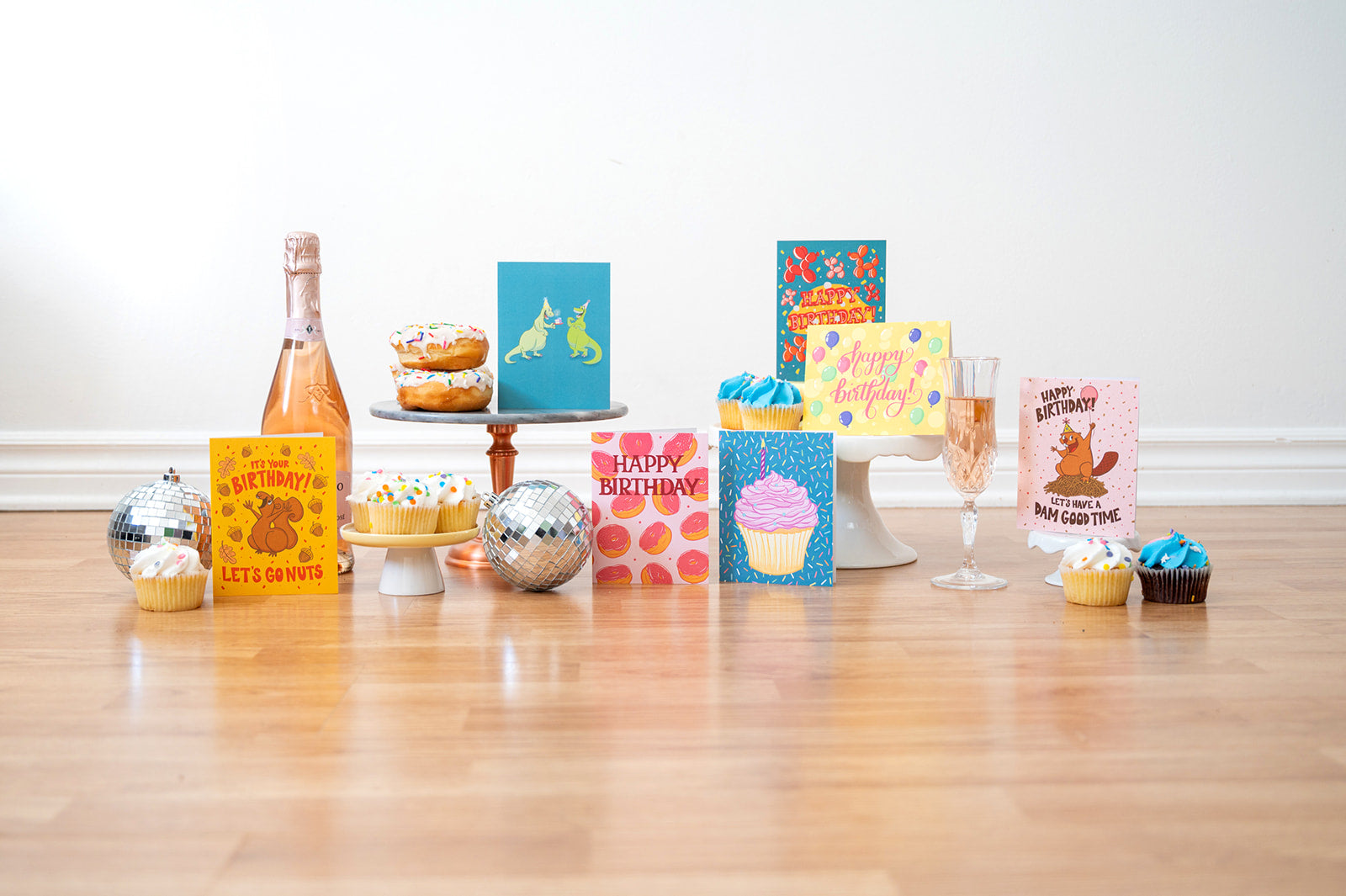 Collection of colorful greeting cards and small celebratory items on a wooden floor.
