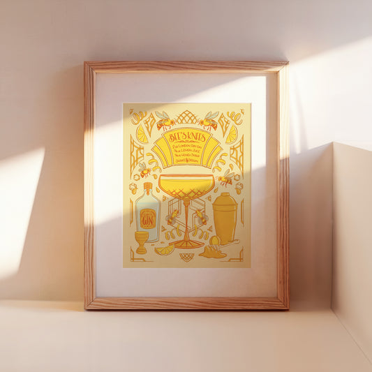 A framed Bee's Knees cocktail recipe illustration leans against a wall.