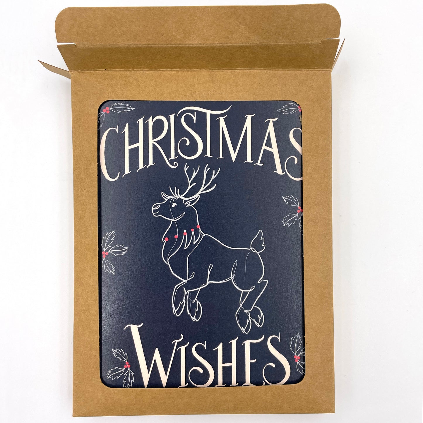 A navy greeting card depicts a flying reindeer in white and red with the word Christmas at the top and Wishes at the bottom. The card in a kraft paper box with a window revealing the card and the top of the box is open.