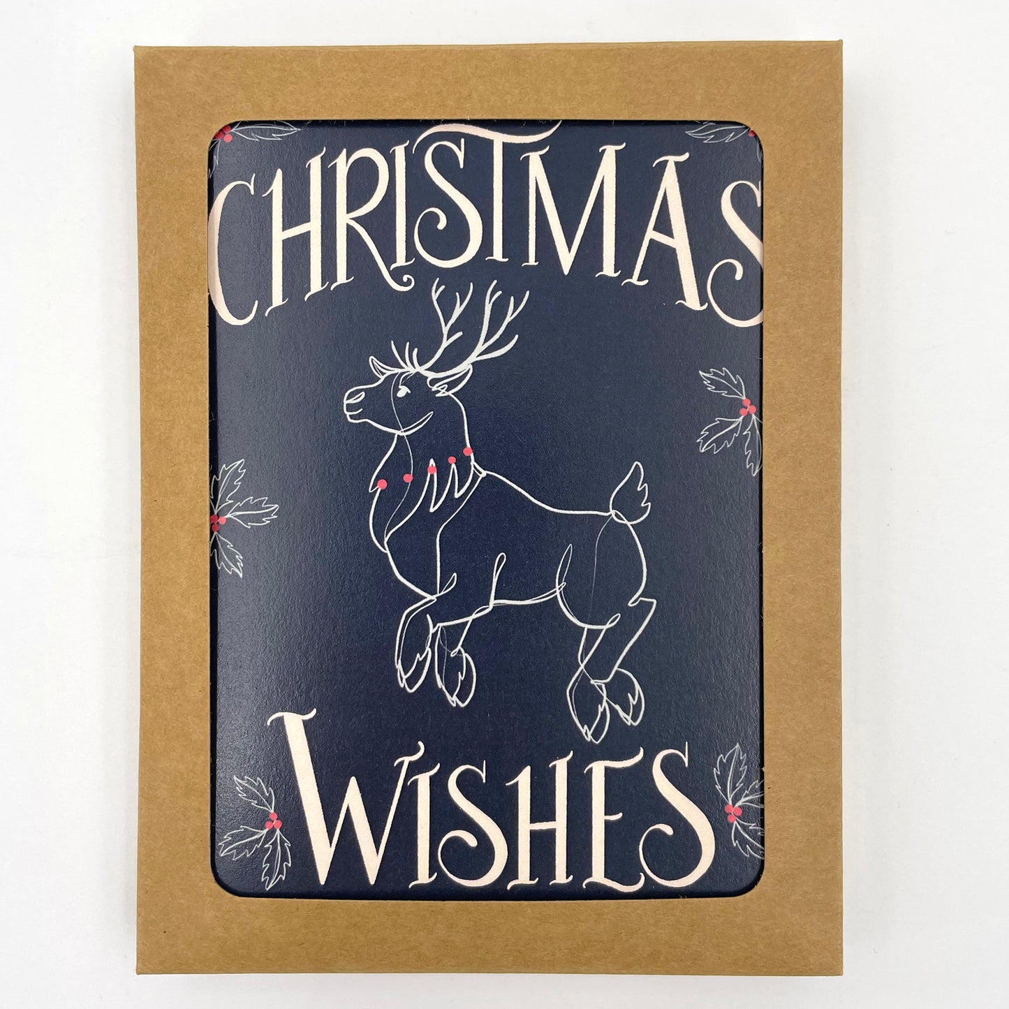 A navy greeting card depicts a flying reindeer in white and red with the word Christmas at the top and Wishes at the bottom. The card in a kraft paper box with a window revealing the card.