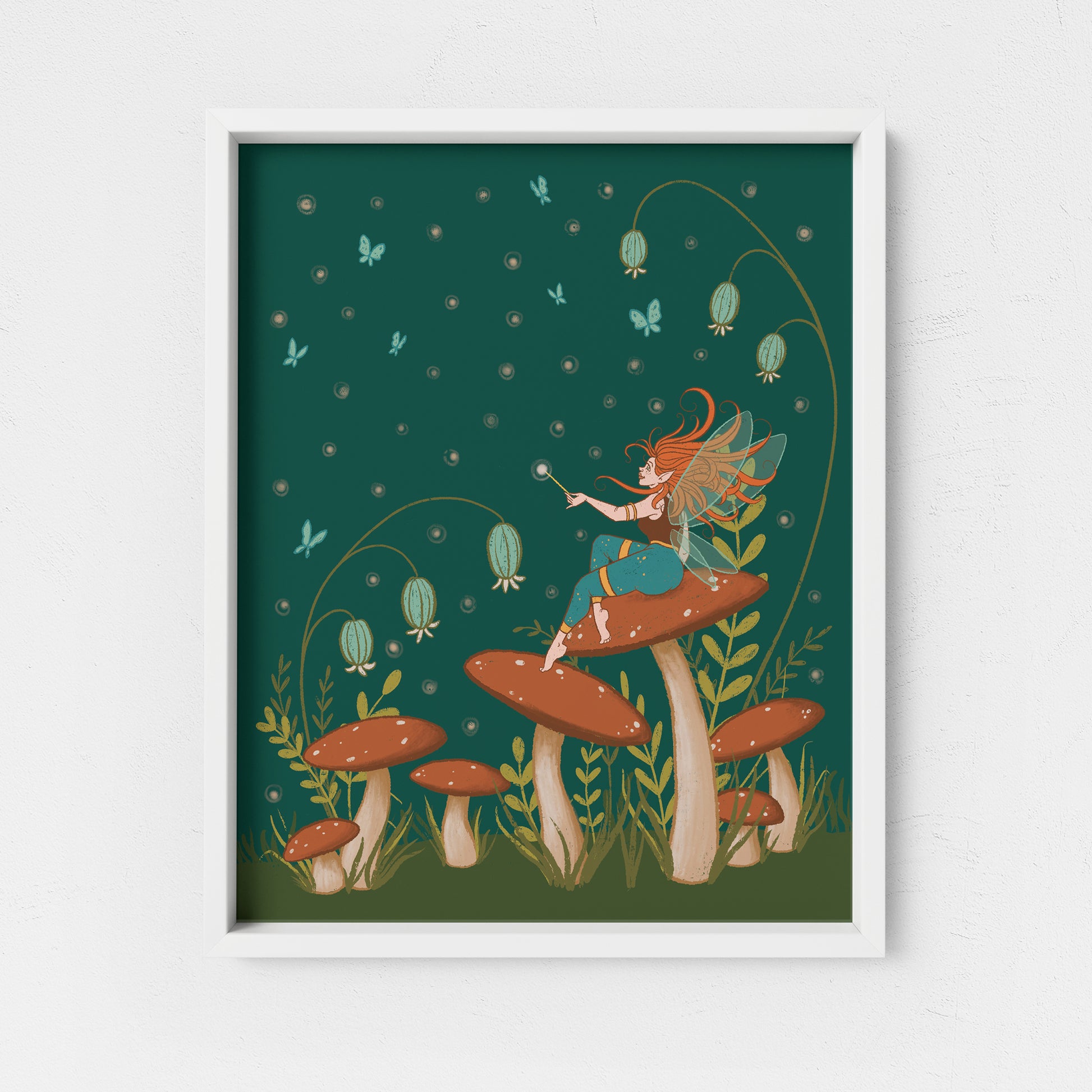 A cottagecore-style illustration shows a winged faerie with turquoise pants sits atop a red-capped mushroom in a field of mushrooms, wildflowers and blue butterflies at night. The print is in a white frame on a white background.