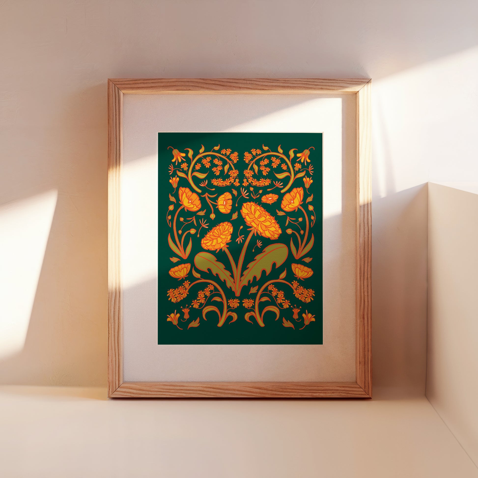 A framed green and yellow dandelion folk floral art print leans against a wall.