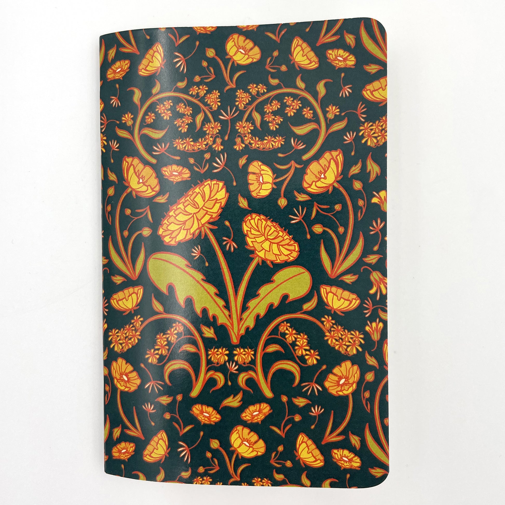 A small closed notebook has a cover patterned with dandelions, buttercups and goldenrod.