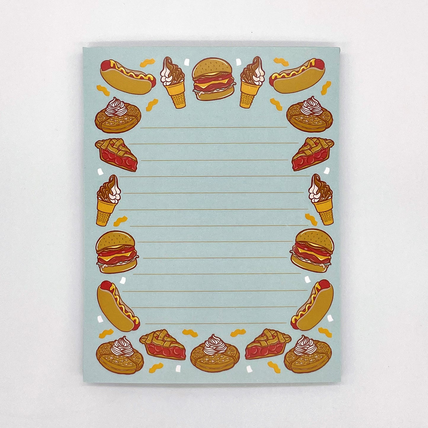 A blue lined notepad features illustrations of burgers, hot dogs, waffles, ice cream and pie.