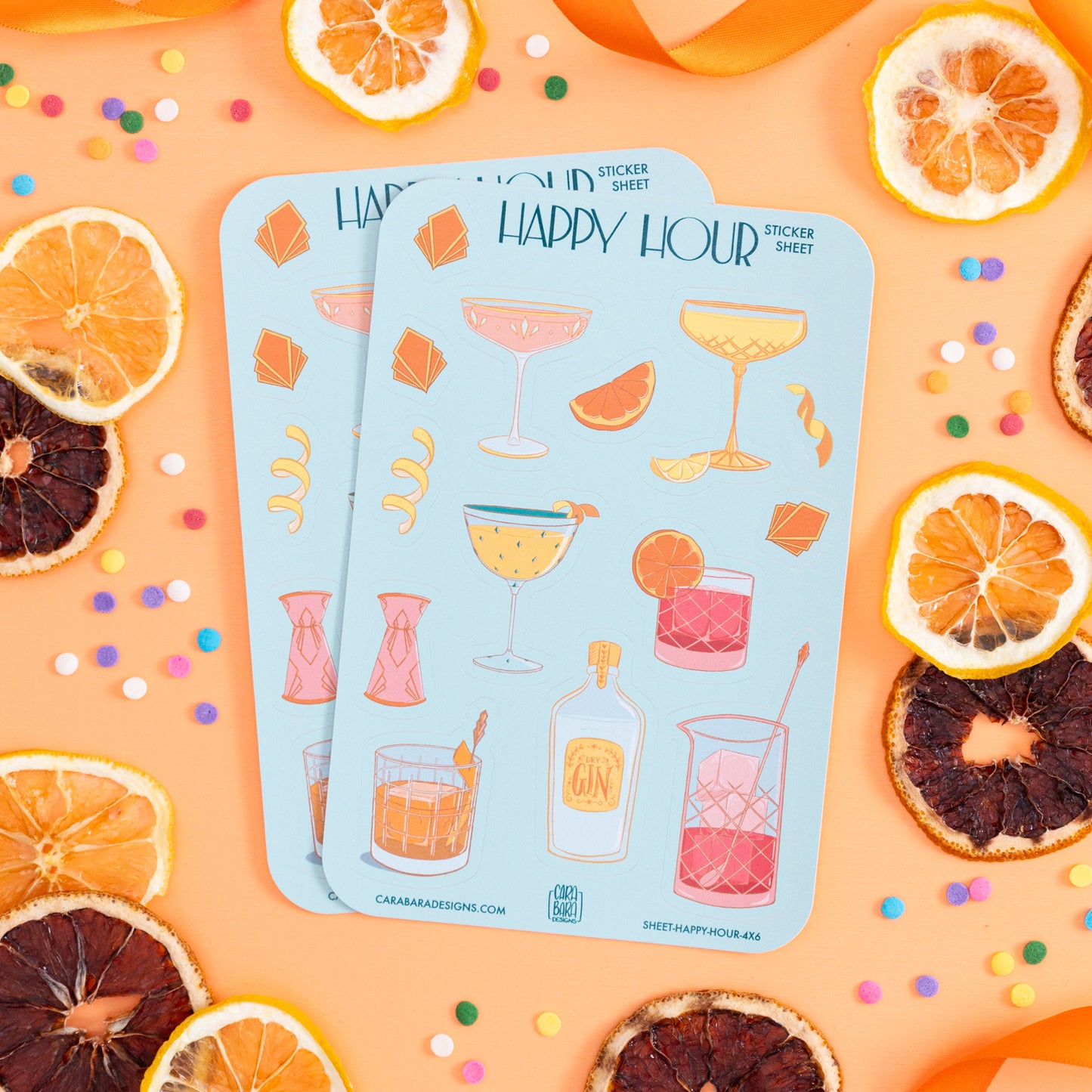 Two art deco cocktail-themed sticker sheets are on an orange background with citrus slices and confetti.