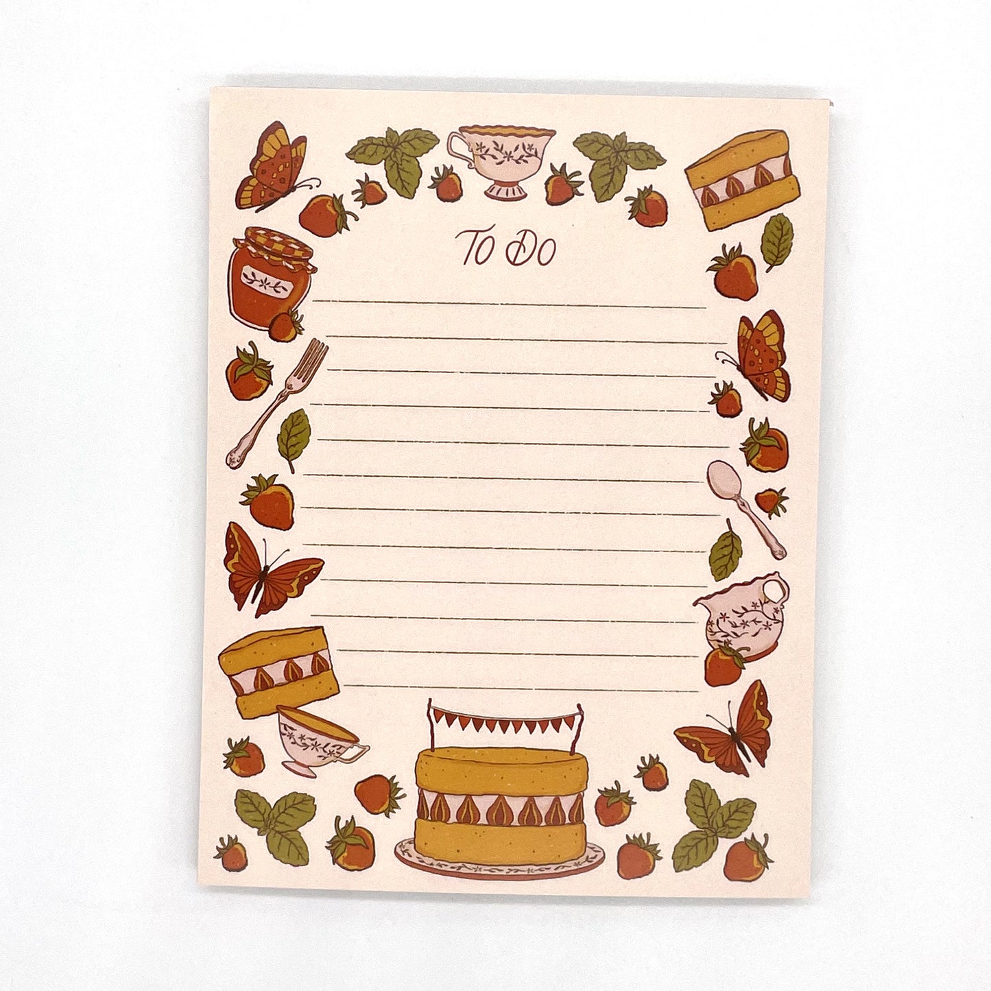 A pink to-do lined cottagecore notepad features illustrated strawberries, mint, cake, tea, and butterflies.