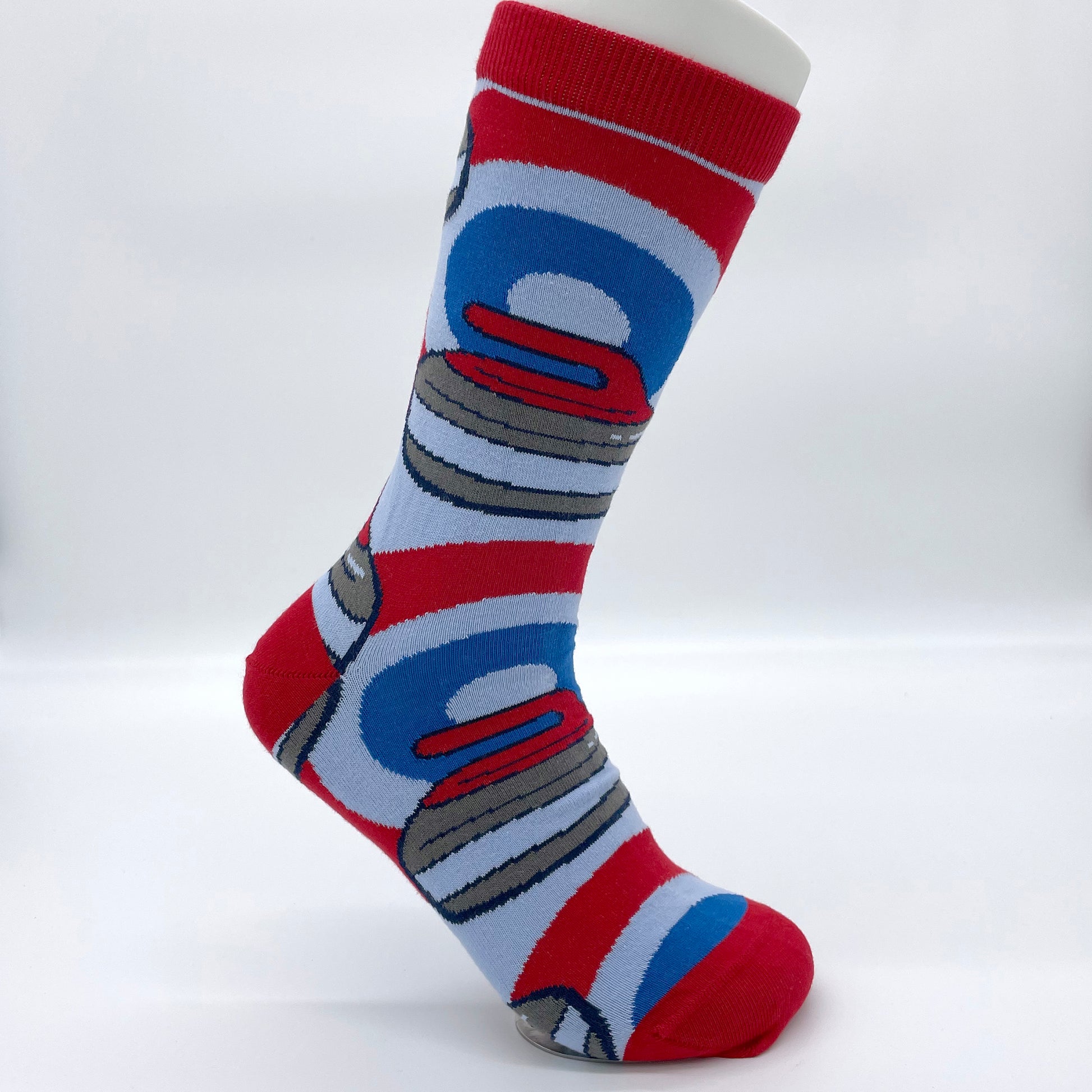 A white sock mannequin sports a blue and red pair of socks patterned with curling rocks.