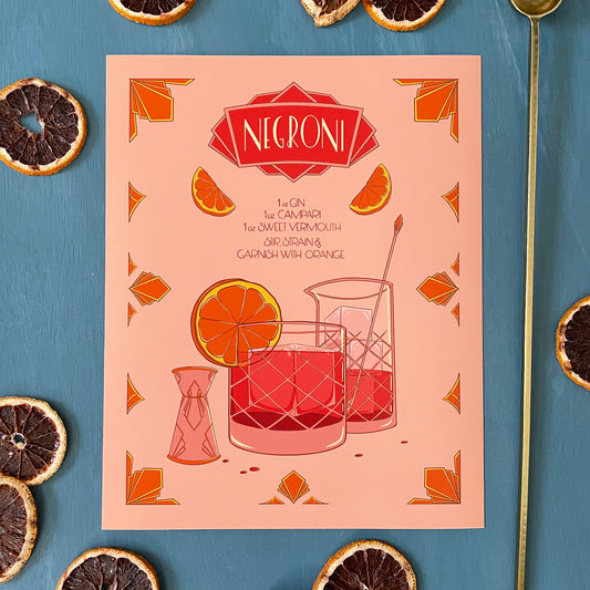An illustrated, hand-lettered negroni recipe in a golden-hour inspired colour palette sits on a blue background surrounded by dehydrated blood orange slices and a barspoon. The illustration featured a mixing glass, a rocks glass filled with negroni and garnished with an orange wedge, a jigger, and art deco ornament.