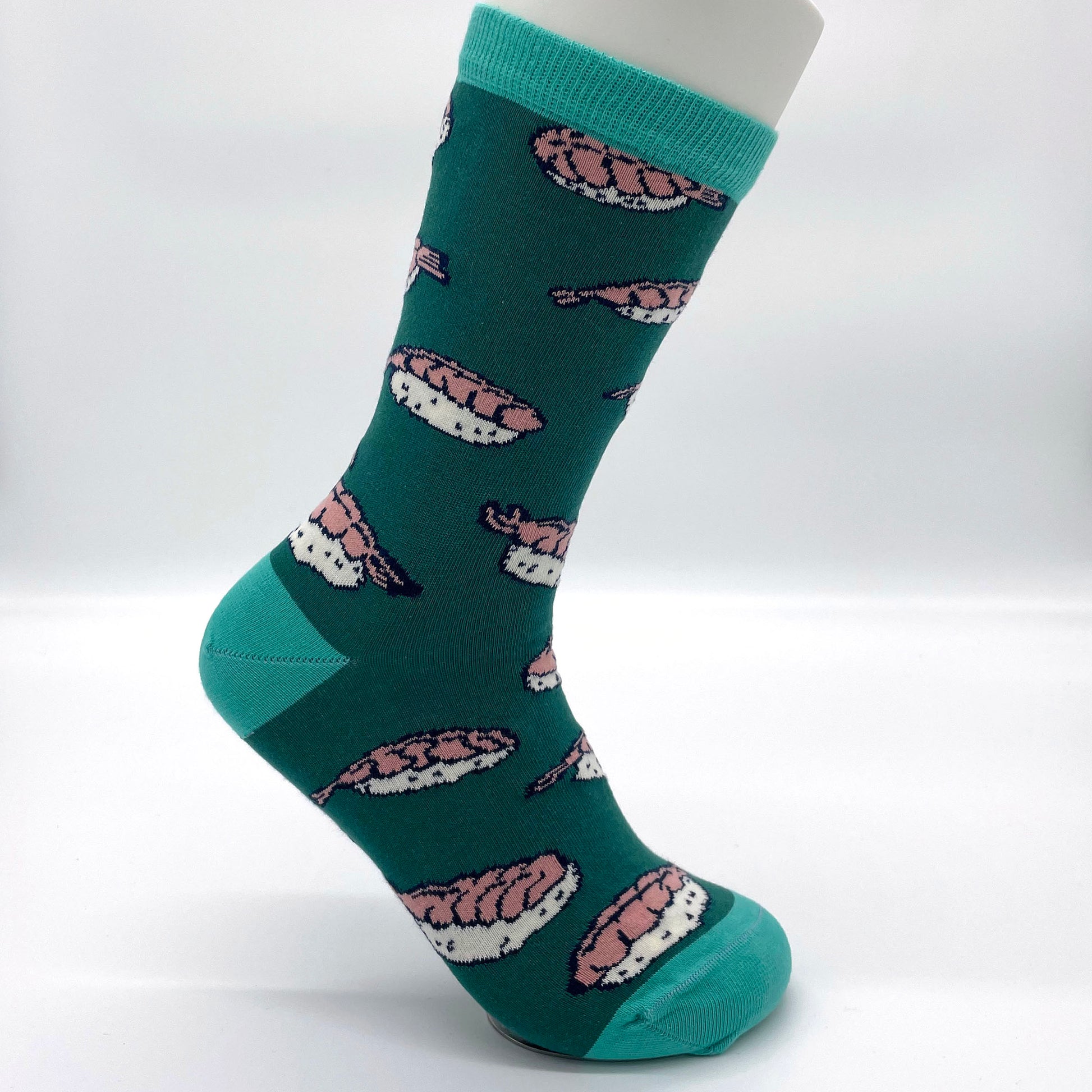 A white sock mannequin sports a teal sock patterned with shrimp nigiri. The welt, heel and toe of the sock are turquoise.