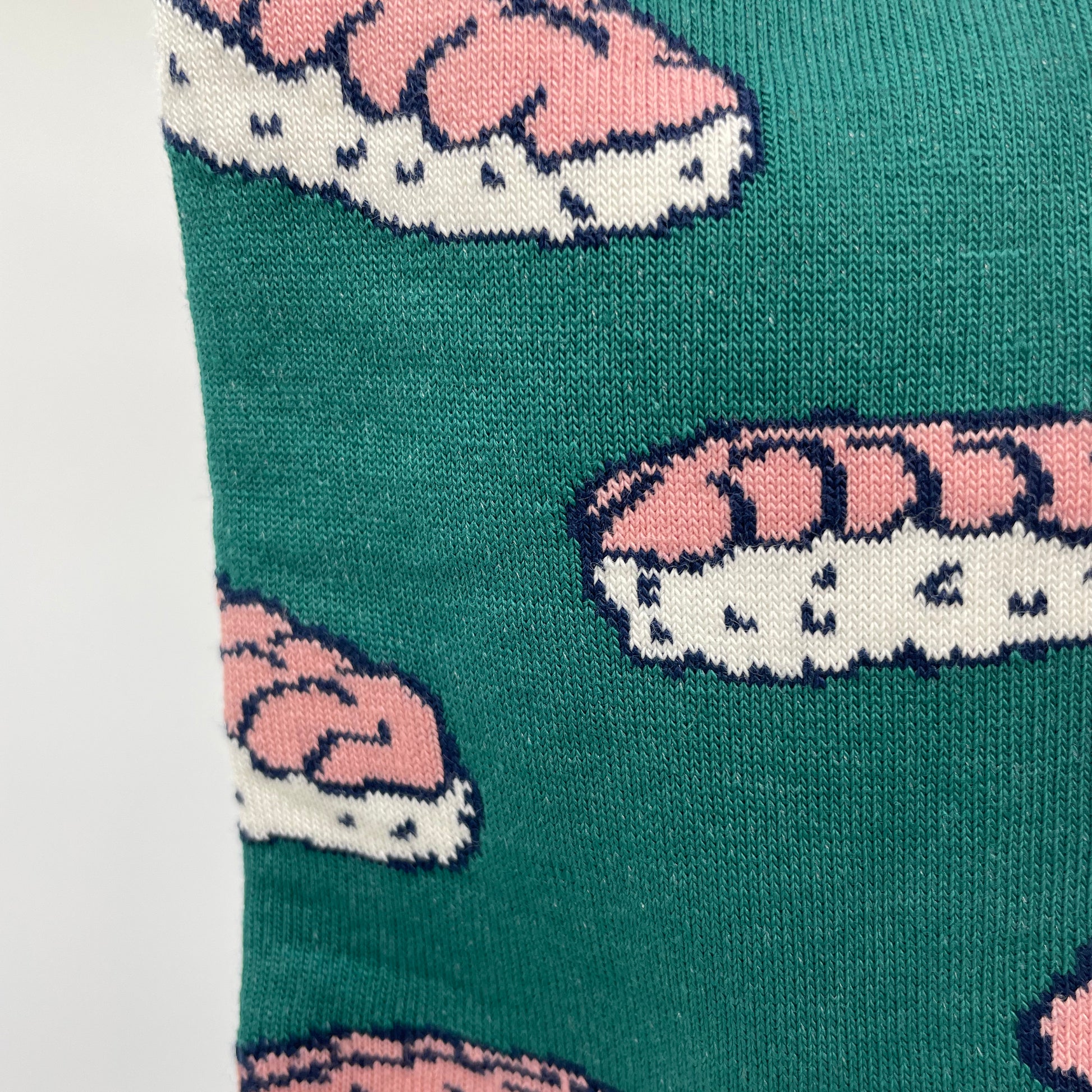 A close-up photo shows detail of a shrimp nigiri pattern woven into teal organic cotton socks.