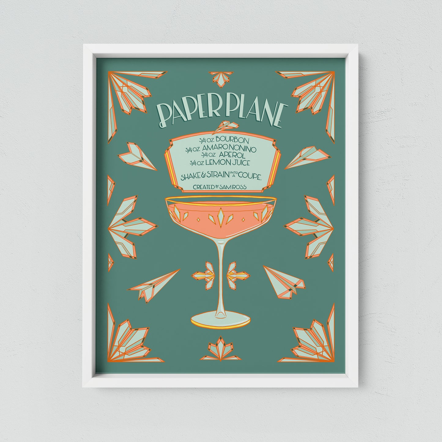 A turquoise and coral illustrated paper plane cocktail recipe hangs framed on a neutral wall.