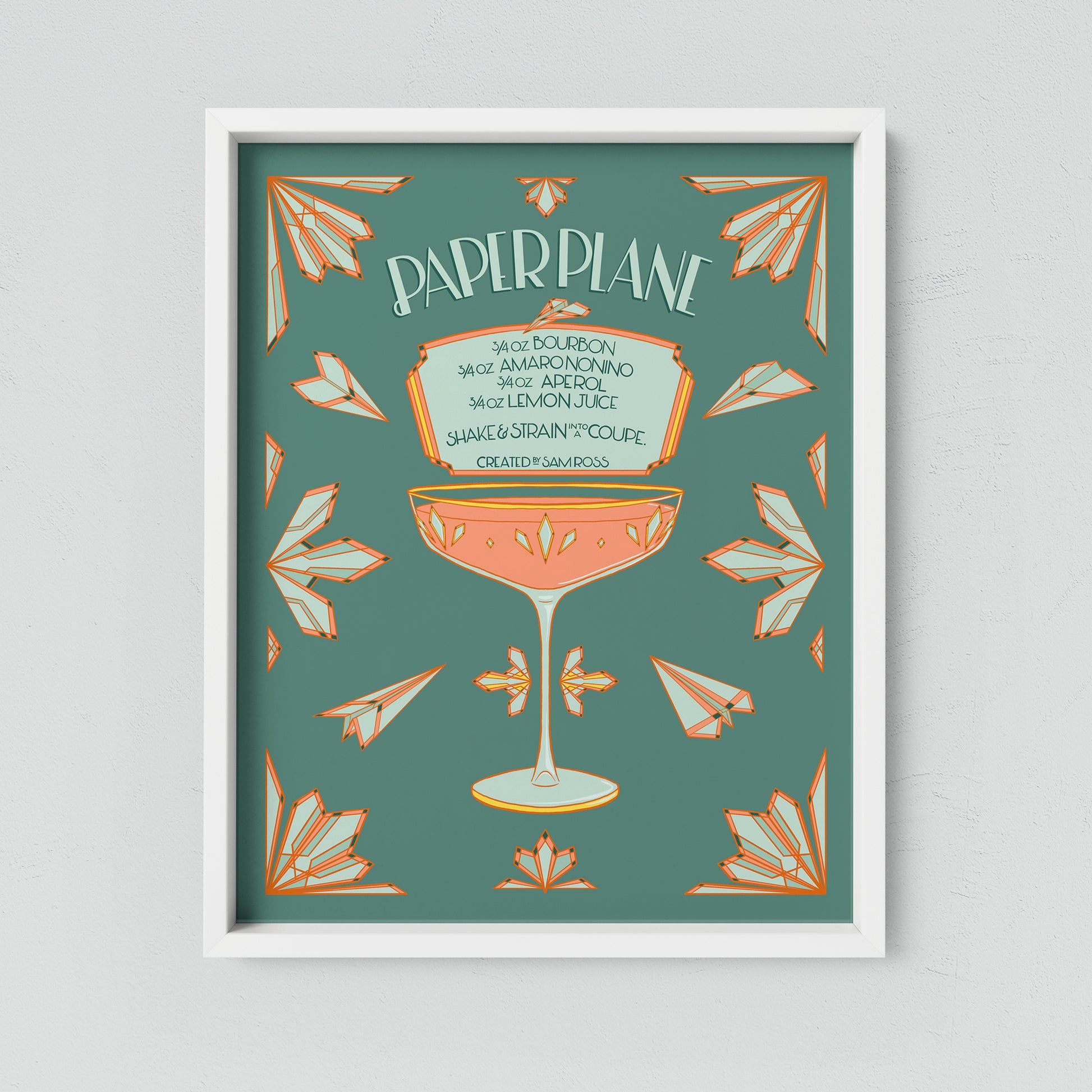 A turquoise and coral illustrated paper plane cocktail recipe hangs framed on a neutral wall.