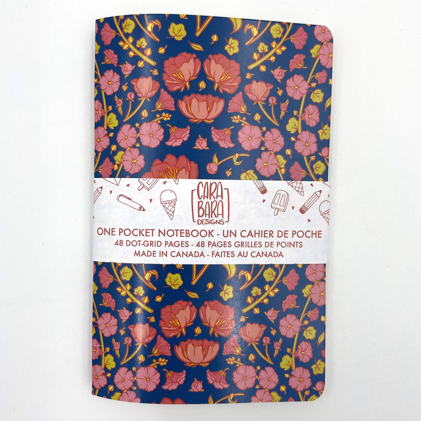 A small closed notebook has a cover that shows a pattern of pink peonies and hollyhocks on a blue background.