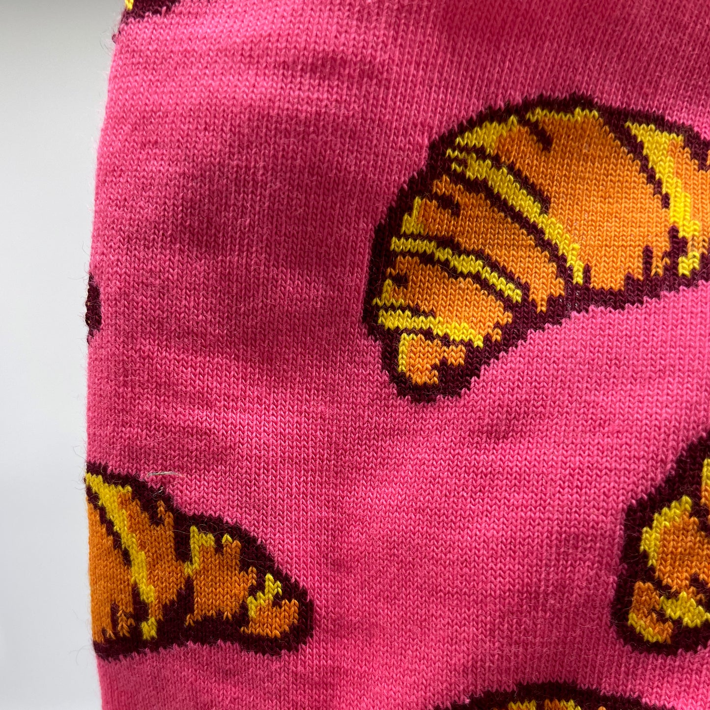 A close-up photo shows a croissant pattern woven into pink organic cotton socks.