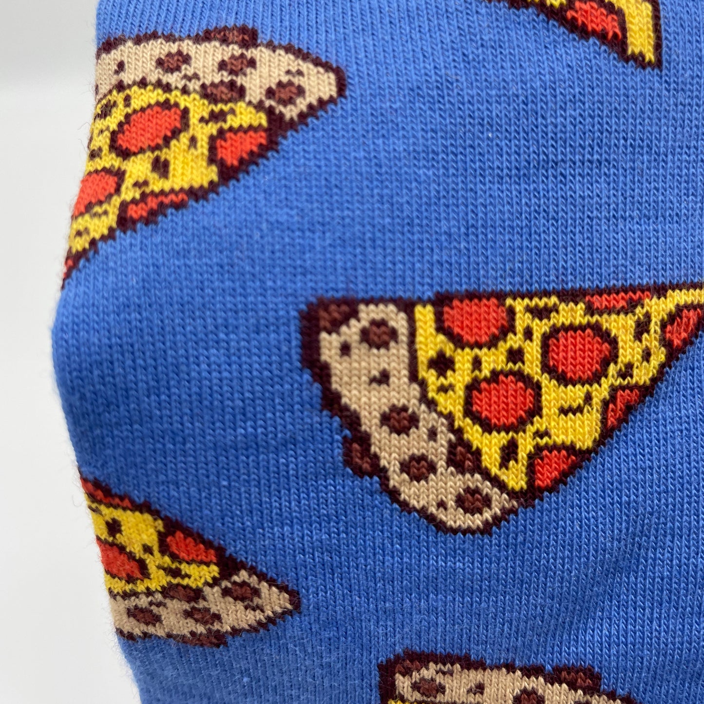 A close-up photo shows detail of a pepperoni pizza pattern woven into blue organic cotton socks.