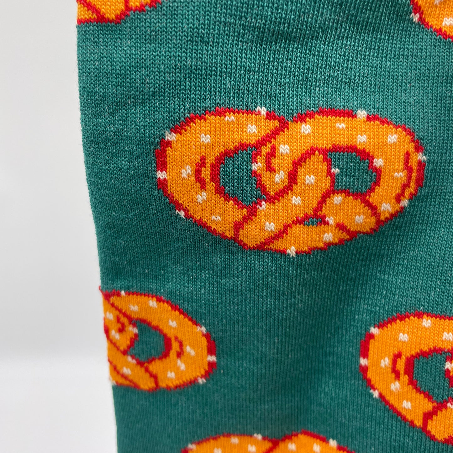 A close-up photo shows detail of a pretzel pattern woven into forest green organic cotton socks.