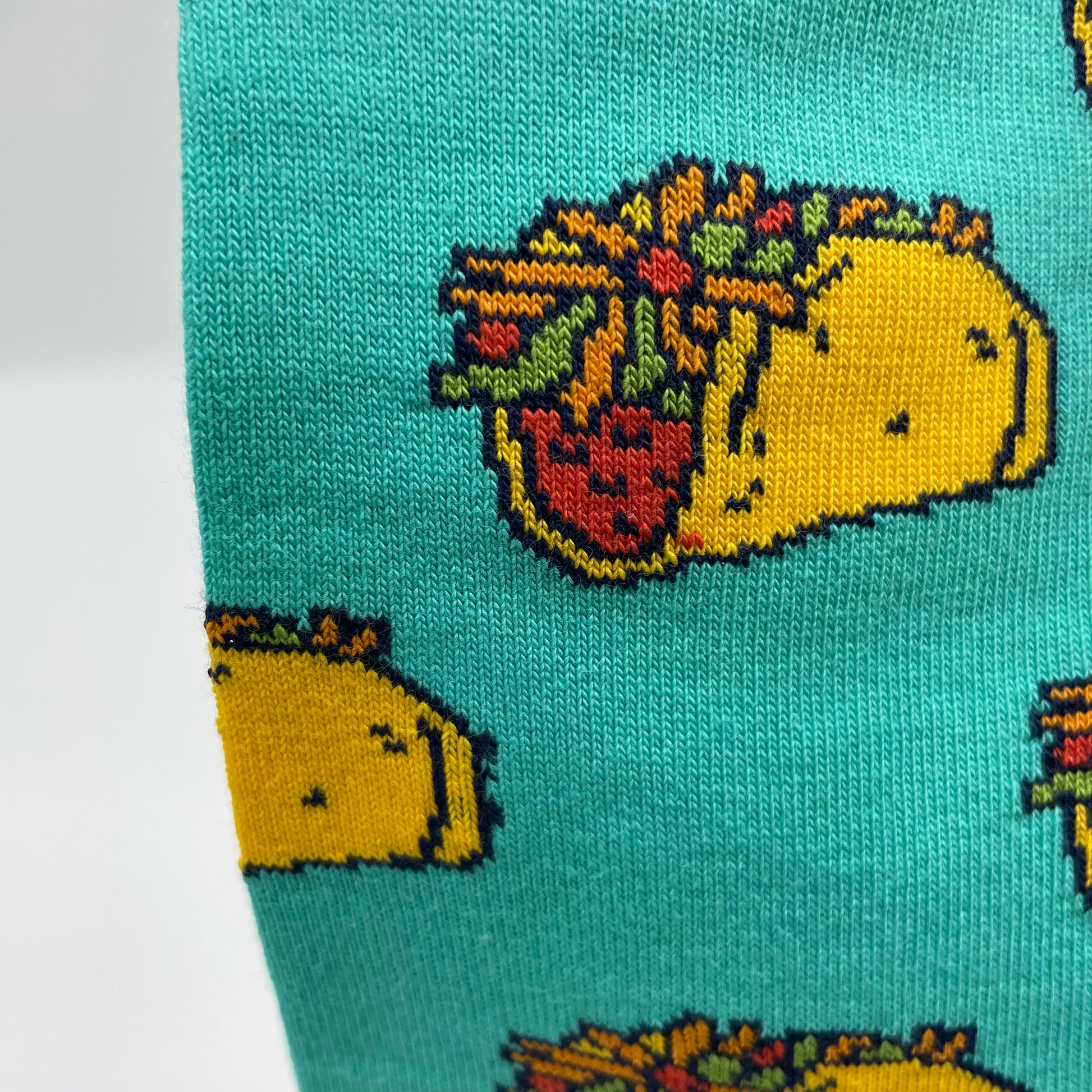 A close-up photo shows detail of a taco pattern woven into turquoise organic cotton socks.