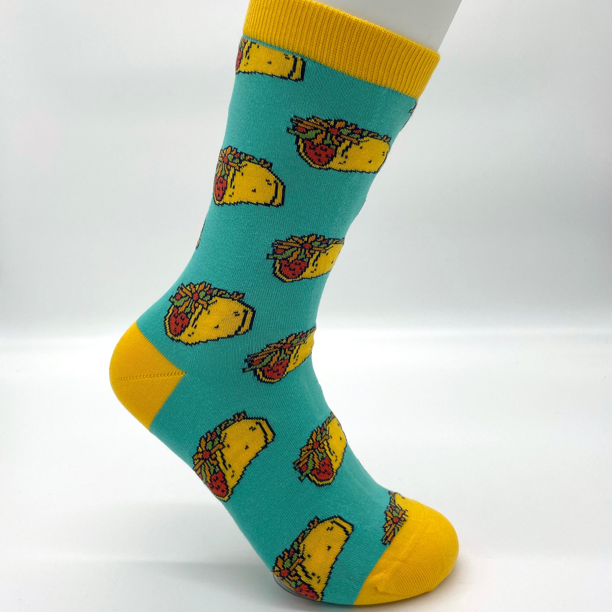 A white sock mannequin sports a turquoise sock patterned with hard-shell tacos. The welt, heel and toe of the sock are yellow.