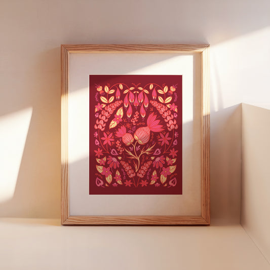 A framed burgundy and pink thistle folk floral leans against a wall.