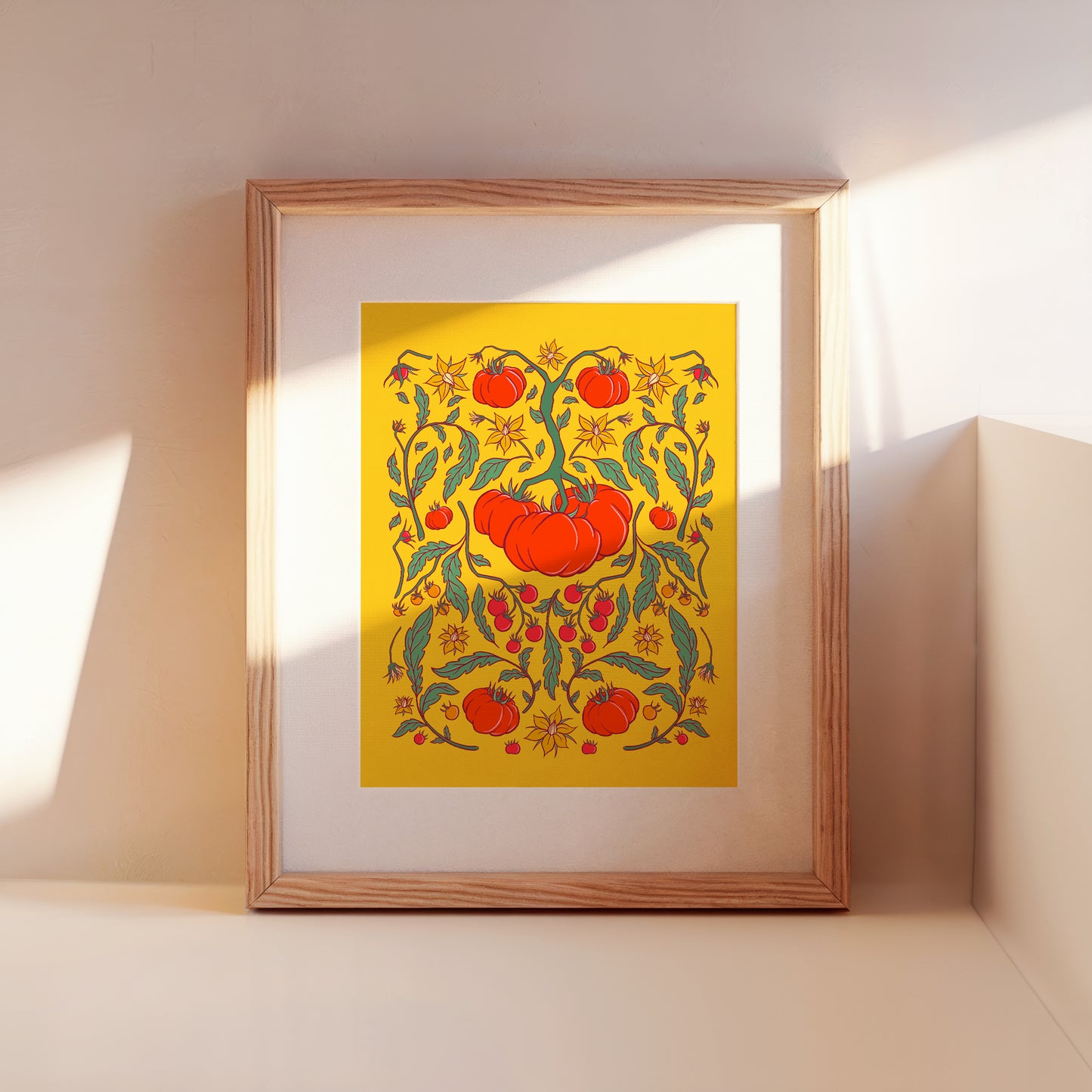 A framed tomato folk floral art print leans against a wall.