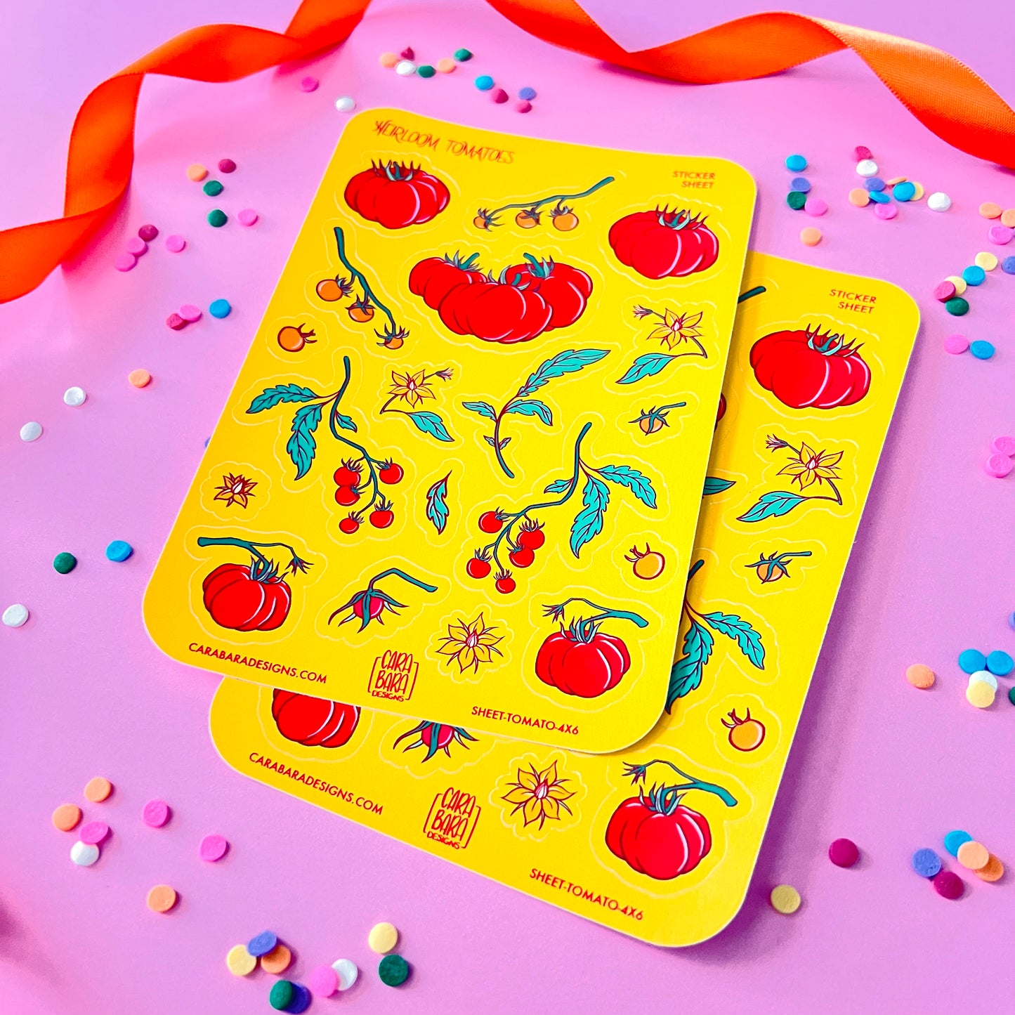 Two yellow sheets of tomato themed stickers lie flat on a pink background.