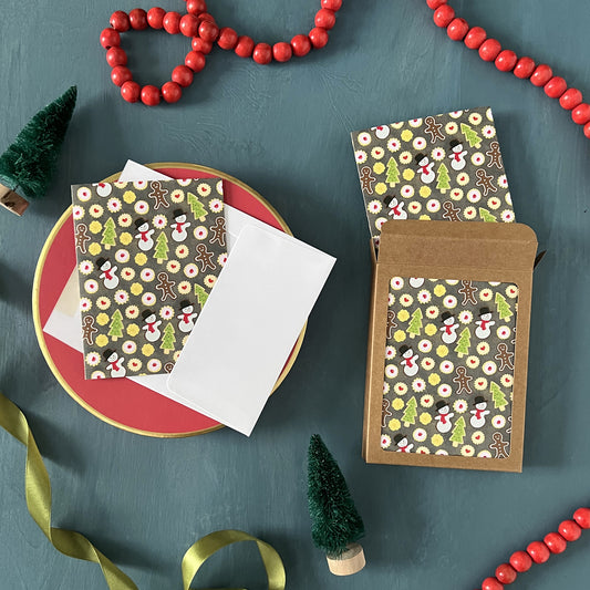 Christmas cookie-themed greeting cards appear on a festive blue background with red beads, green ribbon, and bottle brush trees.