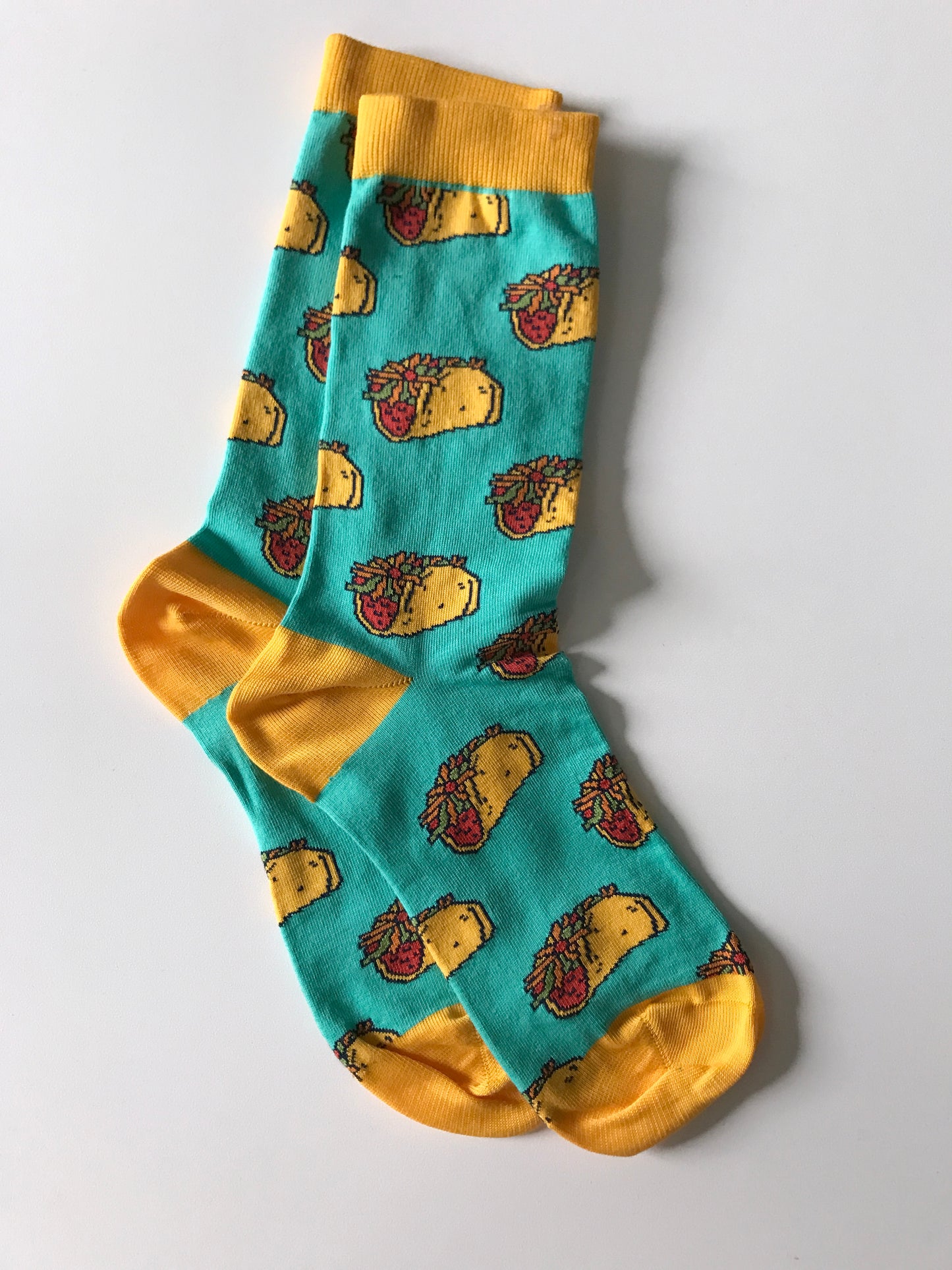 A pair of aqua-blue socks is patterned with hard-shell tacos and has yellow cuffs, heels and toes.