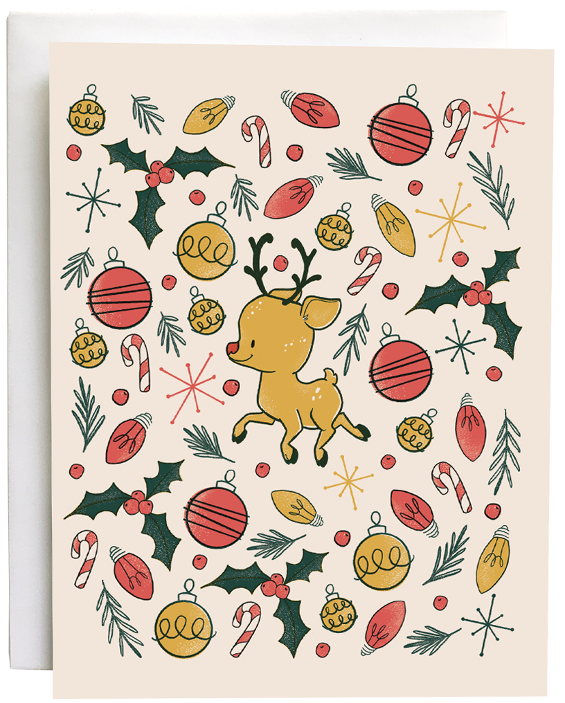 A blush pink card features a cute reindeer surrounded by an explosion of Christmas lights, ornaments, pine branches and holly. The card is against a white envelope on a white background.