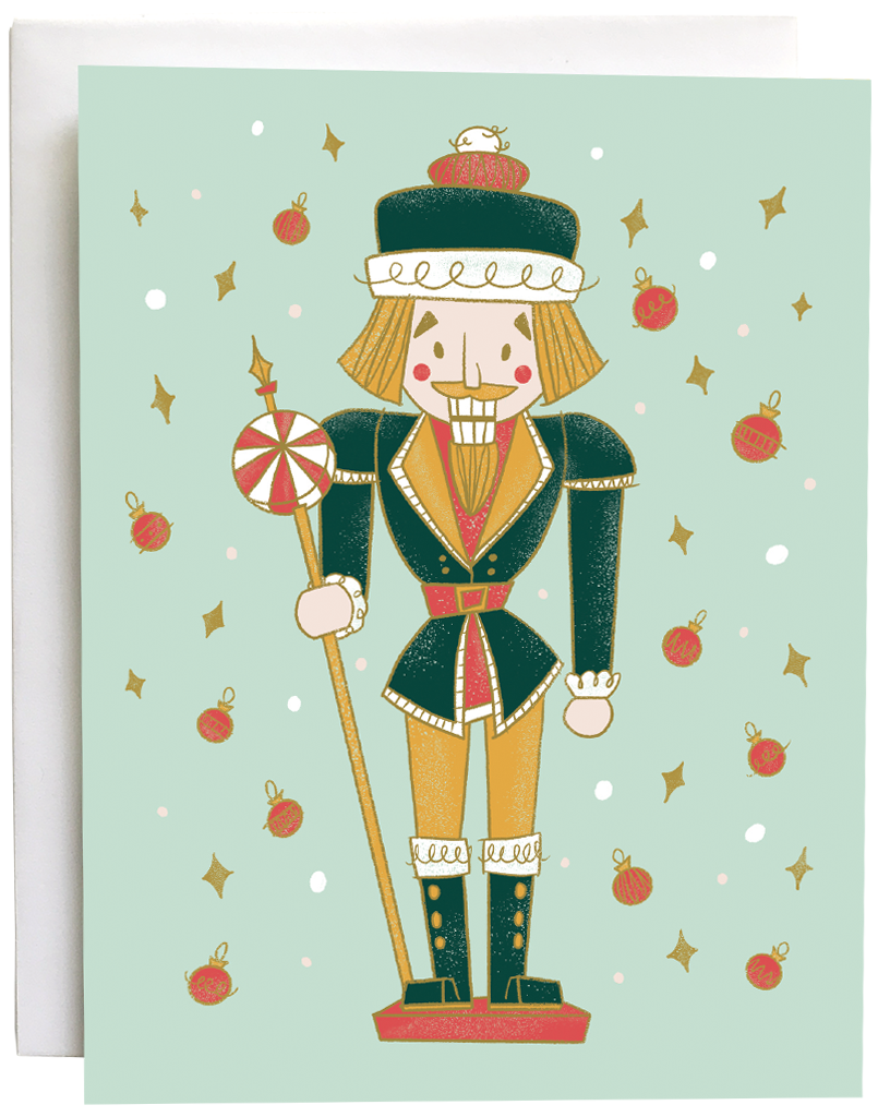 A mint card features a midcentury-style nutcracker in green and yellow, flanked by dots, yellow diamonds and red baubles. The card is against a white envelope on a white background.