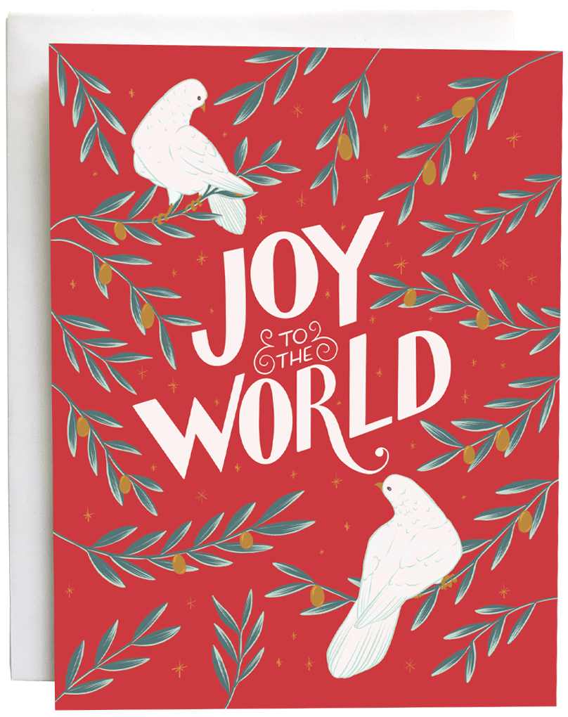 A red greeting card shows two white doves, branches of golden olives, and the hand-lettered words Joy to the World in white. The card is against a white envelope on a white background.